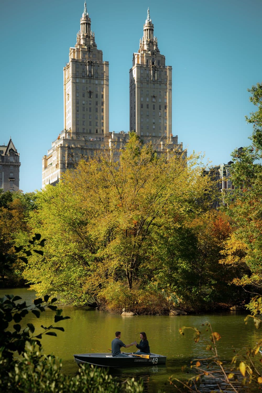 A rowboat on the Lake in Central Park in fall, with the San Remo towers behind